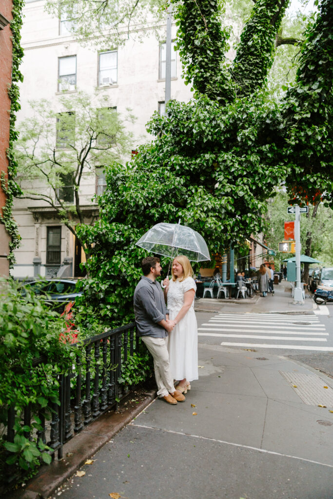 Couple walking through rainy West Village streets during NYC engagement session. Photo by Clay Taylor Photo