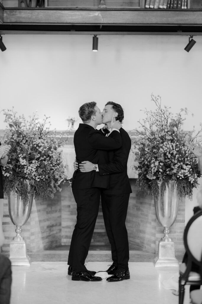 Black and white portrait of Ryan and Spencer kissing after their wedding ceremony in Boston.