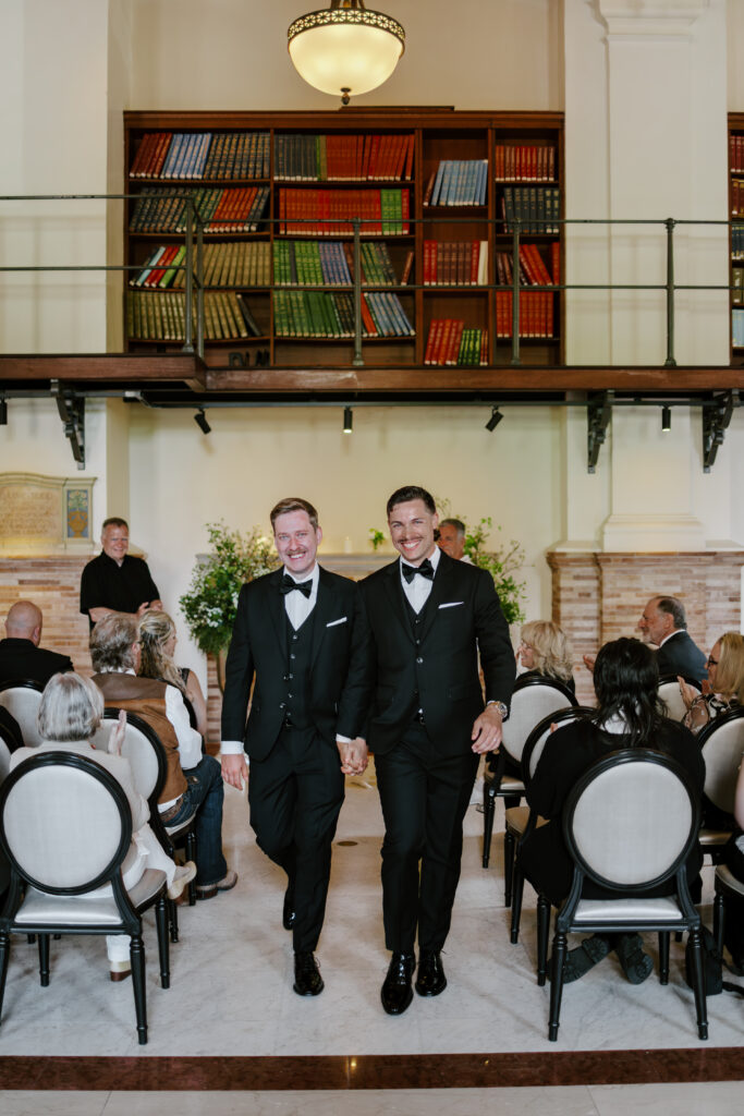 Ryan and Spencer walking back down the aisle together after getting married at the Boston Public Library.