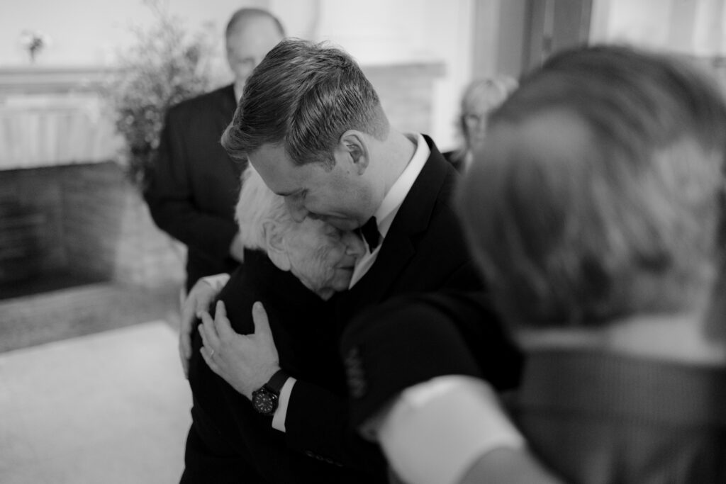 Emotional black and white photo of Ryan hugging a family member after the wedding ceremony.