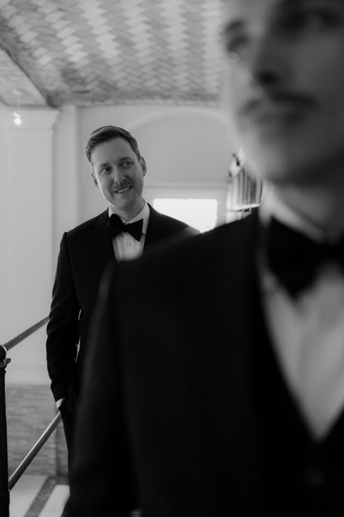 Black and white portrait of Ryan smiling at Spencer inside the Boston Public Library after their wedding ceremony.