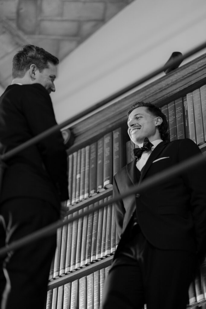 Black and white candid portrait of Spencer smiling at Ryan inside the historic Boston Public Library stacks.