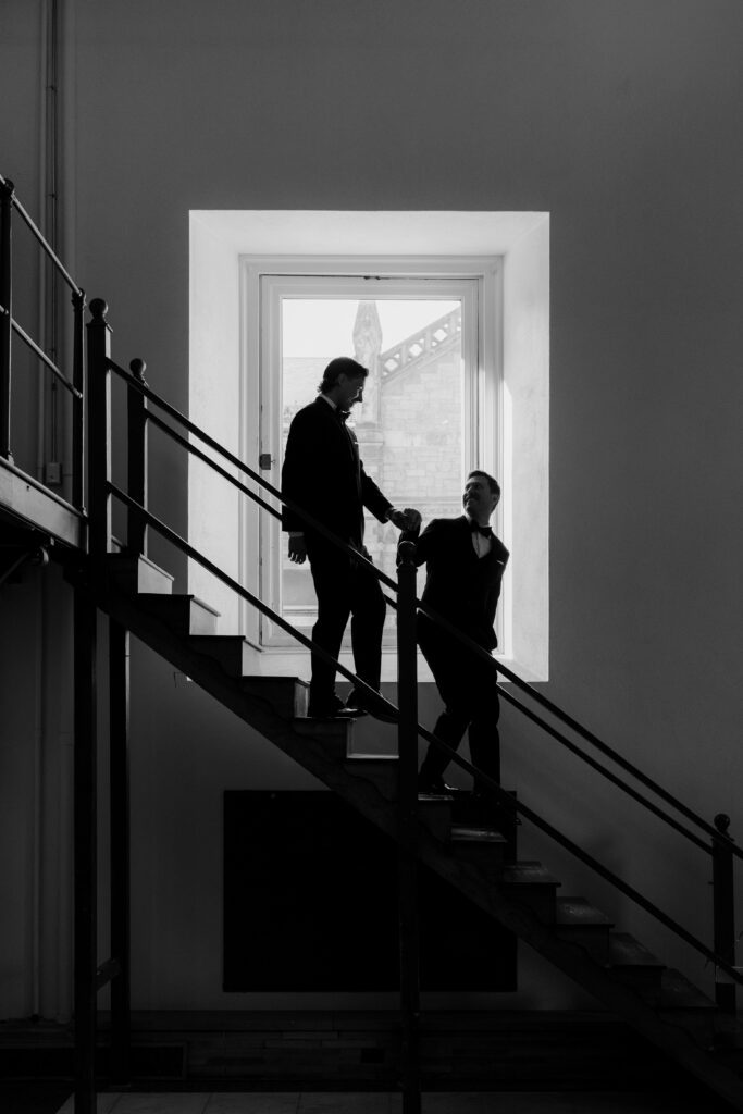 Black and white silhouette portrait of Ryan and Spencer holding hands on the staircase inside the Boston Public Library.