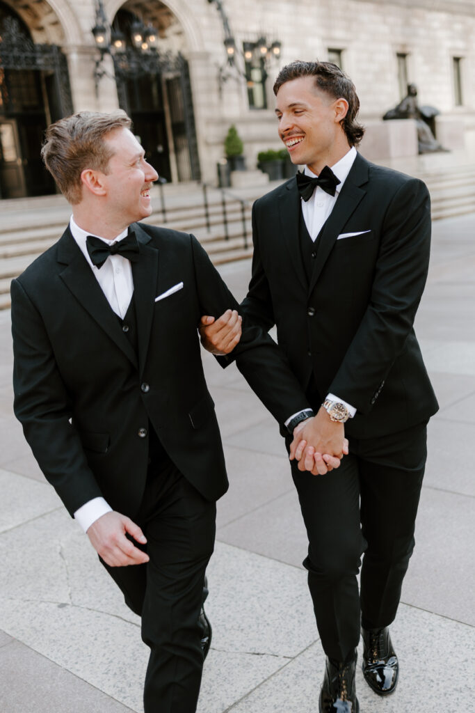 Ryan and Spencer laughing together outside the Boston Public Library in downtown Boston after their wedding ceremony.