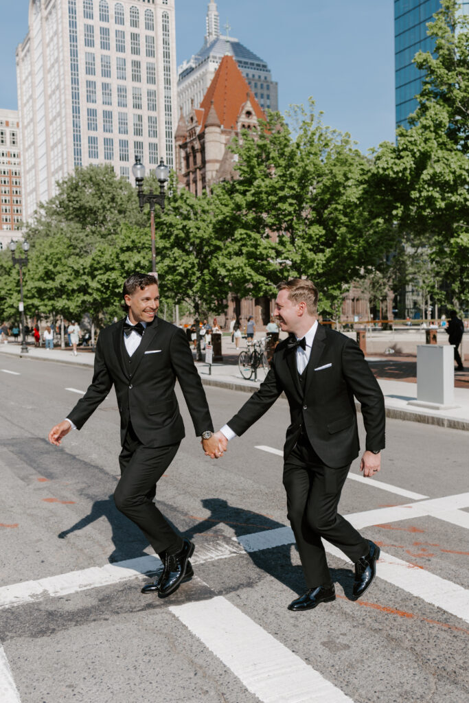 Ryan and Spencer crossing the street together in downtown Boston near the Boston Public Library on their wedding day.