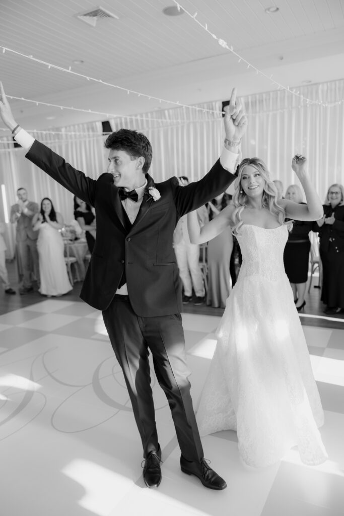Black and white photo of bride and groom walking into wedding reception