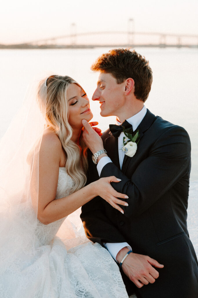 Close up golden hour photo of groom holding brides chin as they look at eachother