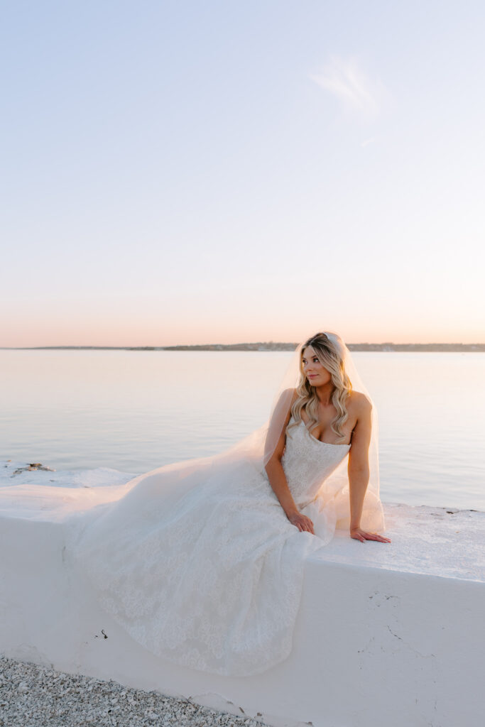 Sunset bridal portrait of bride staring off into the water at Belle Mer