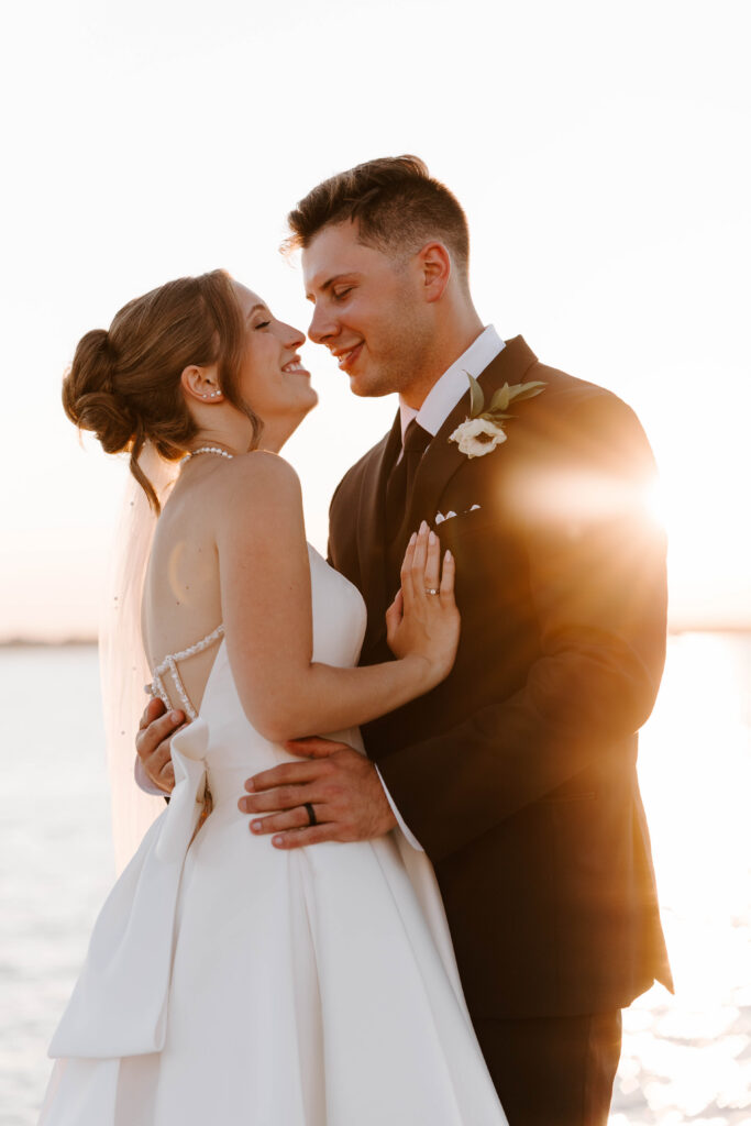 Bride and groom sunset portrait with them looking at each other with the ocean in the background