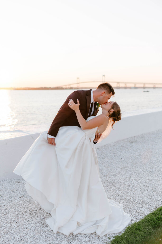 Groom dipping bride at sunset on wedding day in Newport, Rhode Island