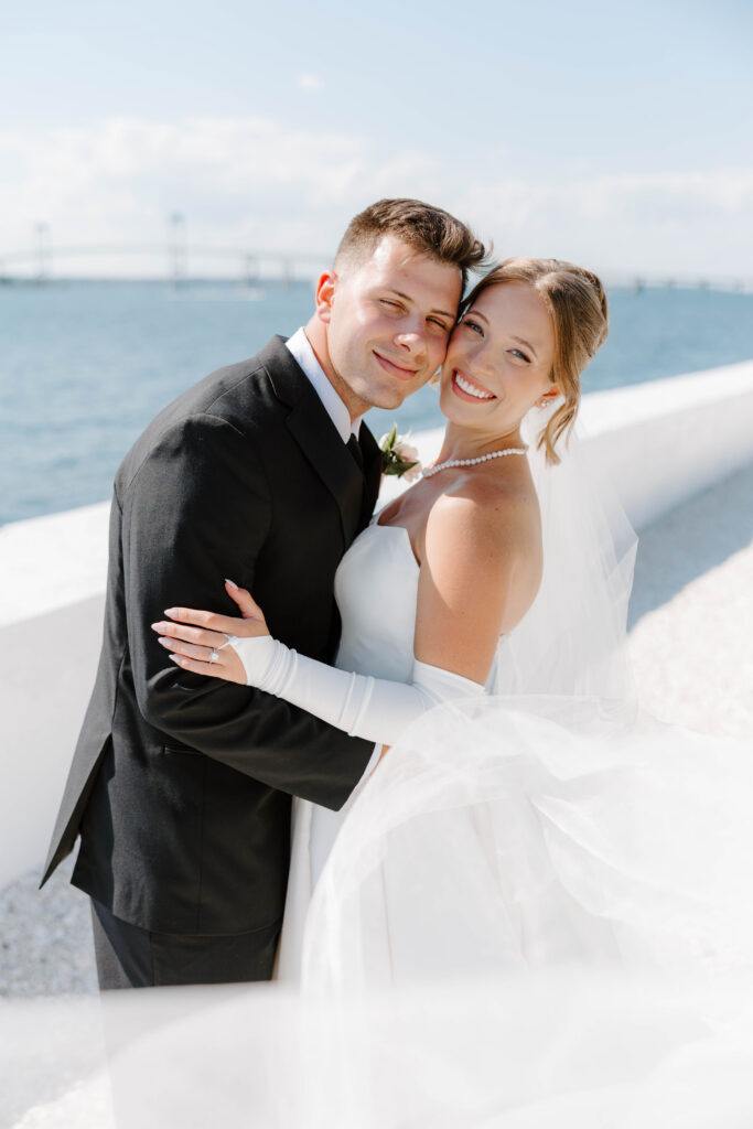 Bride and groom portrait smiling at camera with ocean in background in Newport, Rhode Island