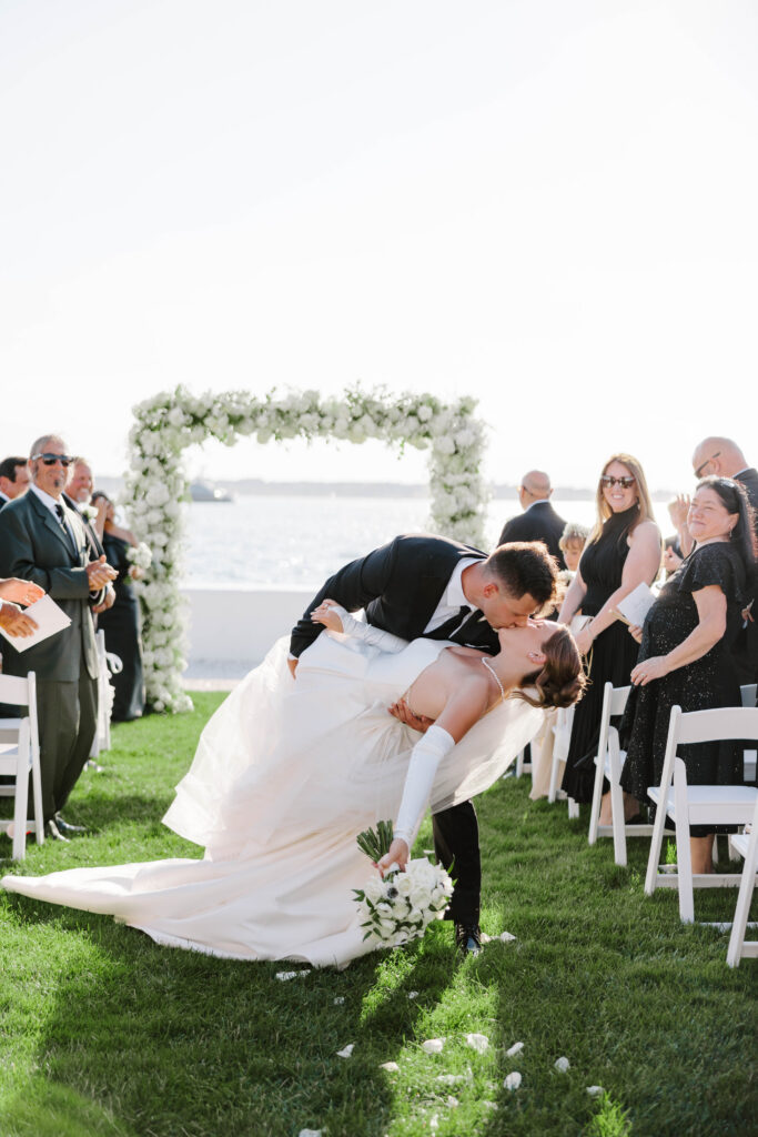 Groom dips bride at end of ceremony aisle in Newport
