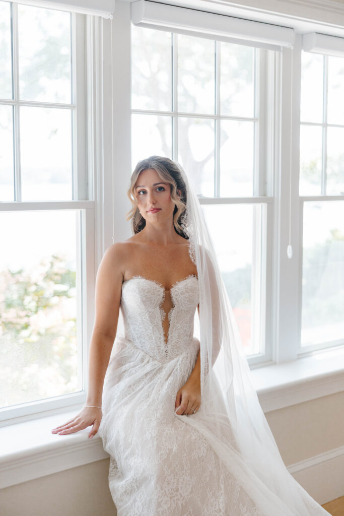 bride sits next to window in bridal suite