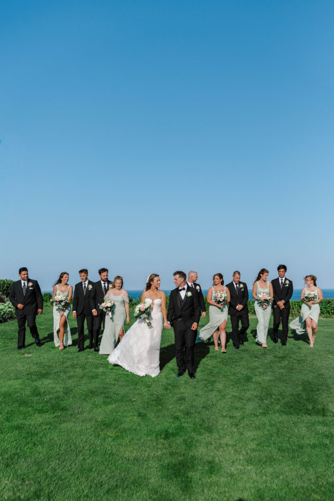 wedding party walks with couple on wedding day in cape cod massachuetts