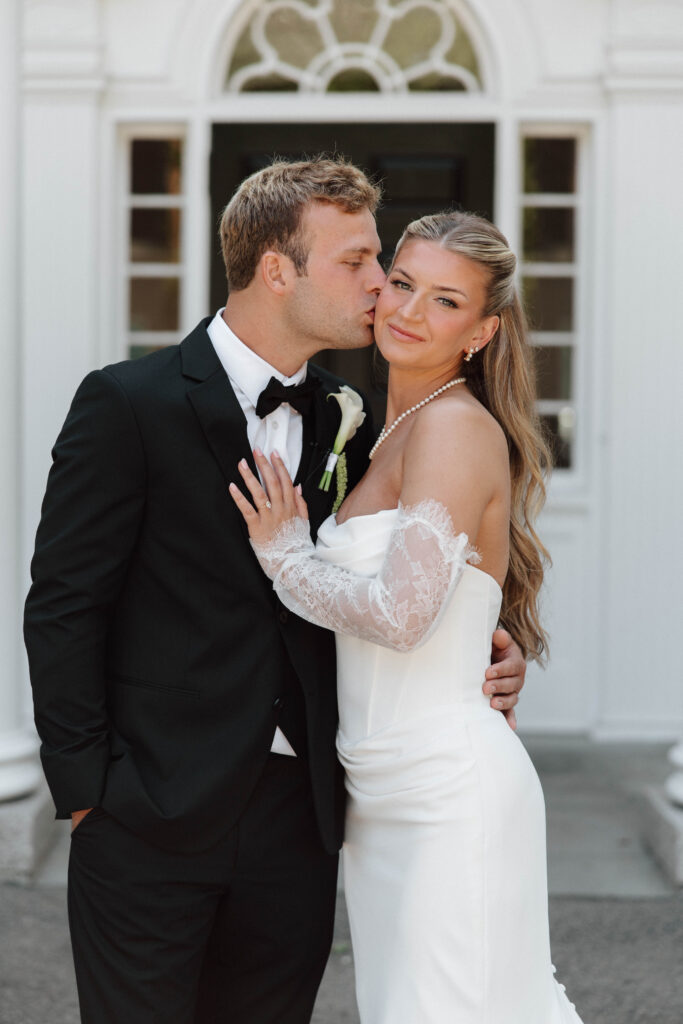 Groom kisses bride on cheek at historic wedding venue in Massachusetts