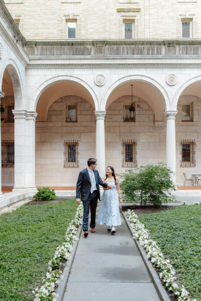 Man and woman walk and hold hands in the courtyard of the Boston Public Library