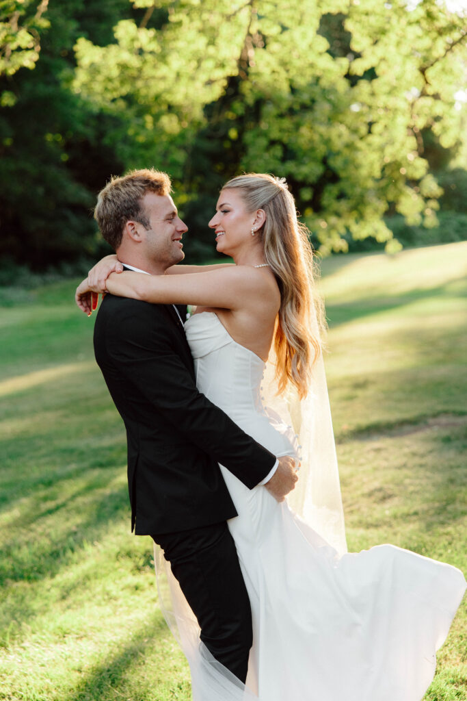 Groom lifts bride in portrait on wedding day in Massachusetts