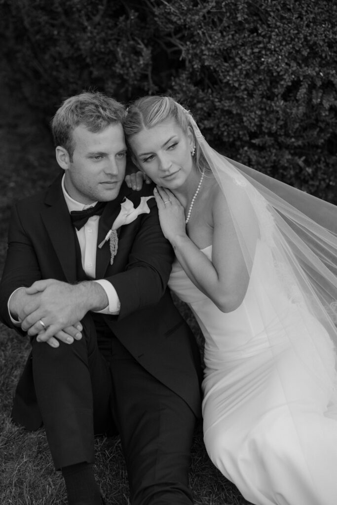 Black and white portrait of bride and groom cuddling in garden