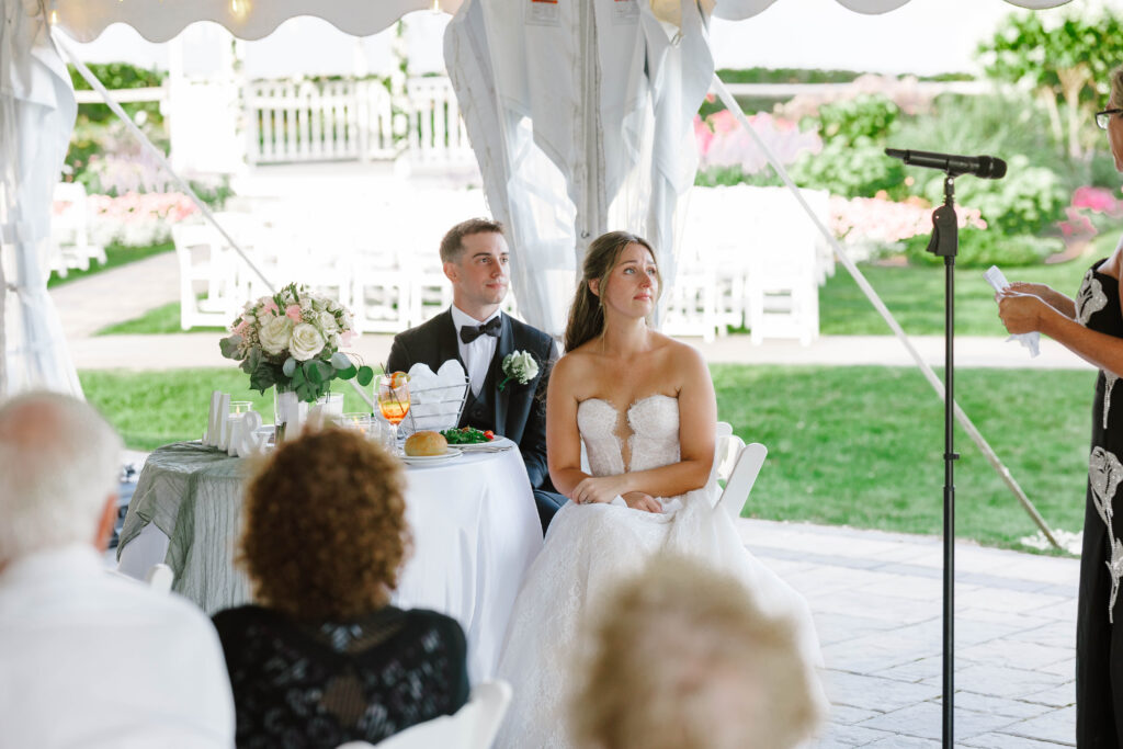 bride and groom listen to emotional speech during reception