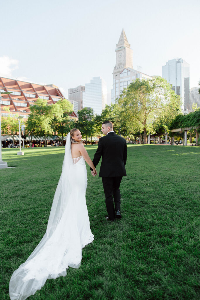 Bride and groom walk in Christopher Columbus park in Boston, Massachusetts