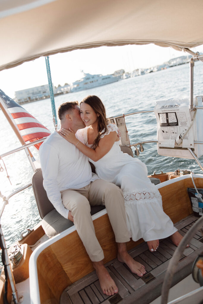 Man and woman sit on sailboat engagement session in Rhode Island