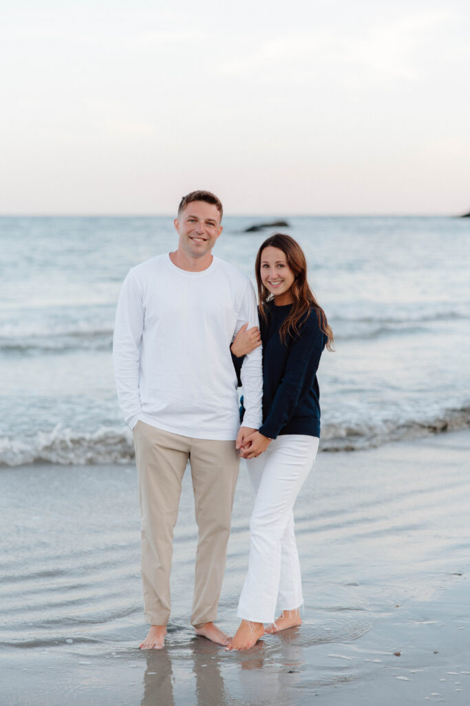 Man and woman look at camera at Second Beach in Newport, Rhode Island during engagement session