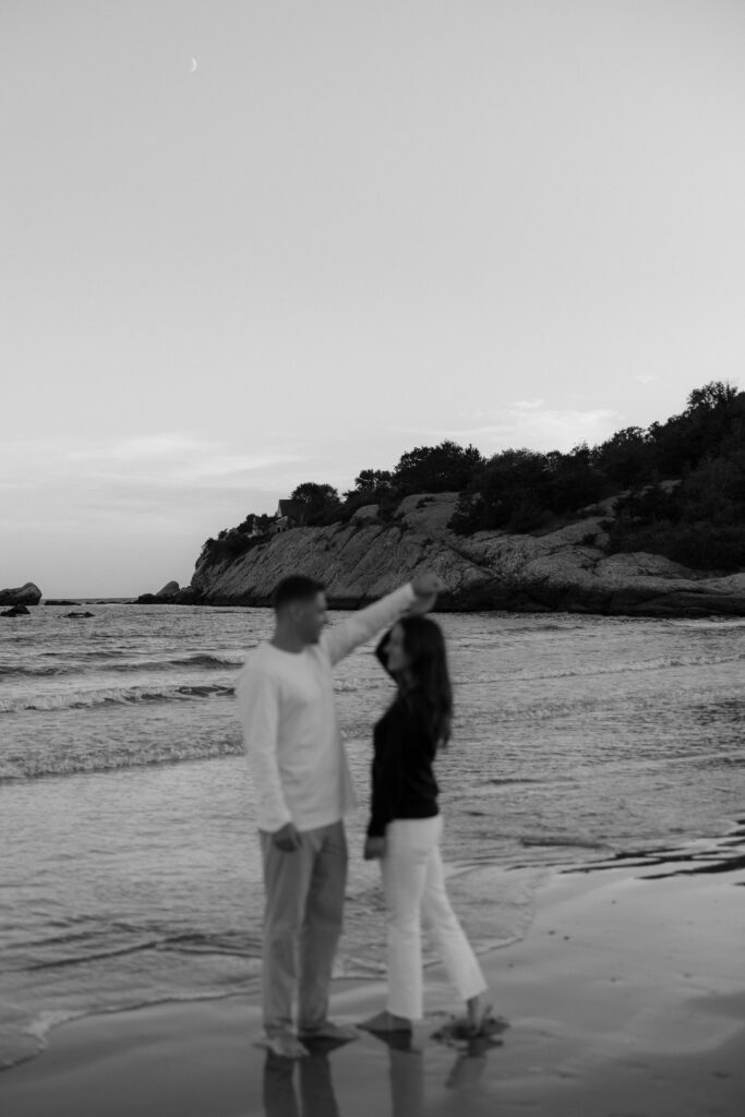 Black and white photo of man twirling woman on the beach